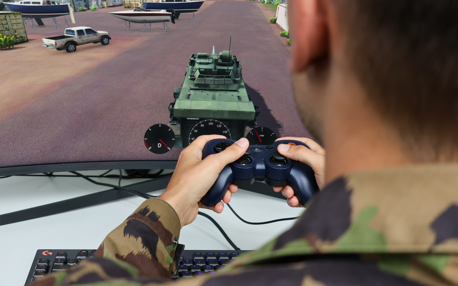 A man in a camouflage suit holds a Playstation controller in his hand and plays a simulation game