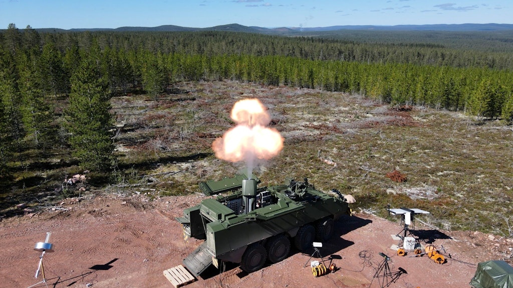 In the foreground, the observer can see the weapons system “12 cm Mortar 16” during an aimed shot. Various measurement systems are discernible, distributed around the weapons system. 