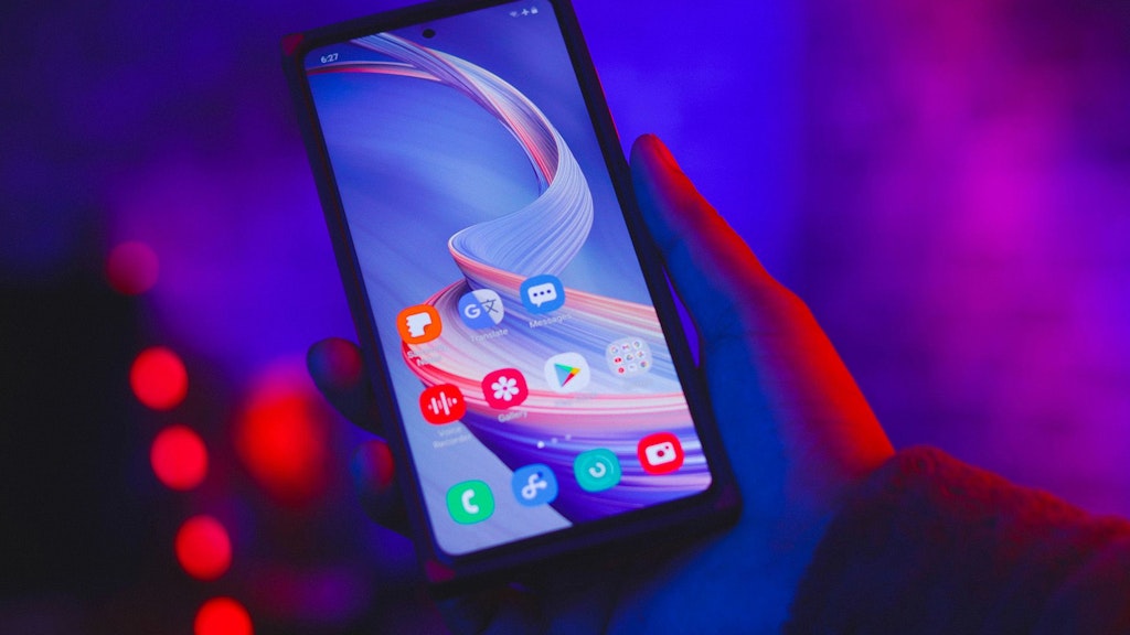 Mobile phone in hand with blue-violet background