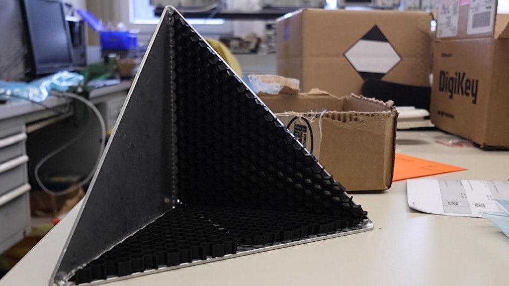 Triangular black modules with holes, located in a pyramid-shaped container. 