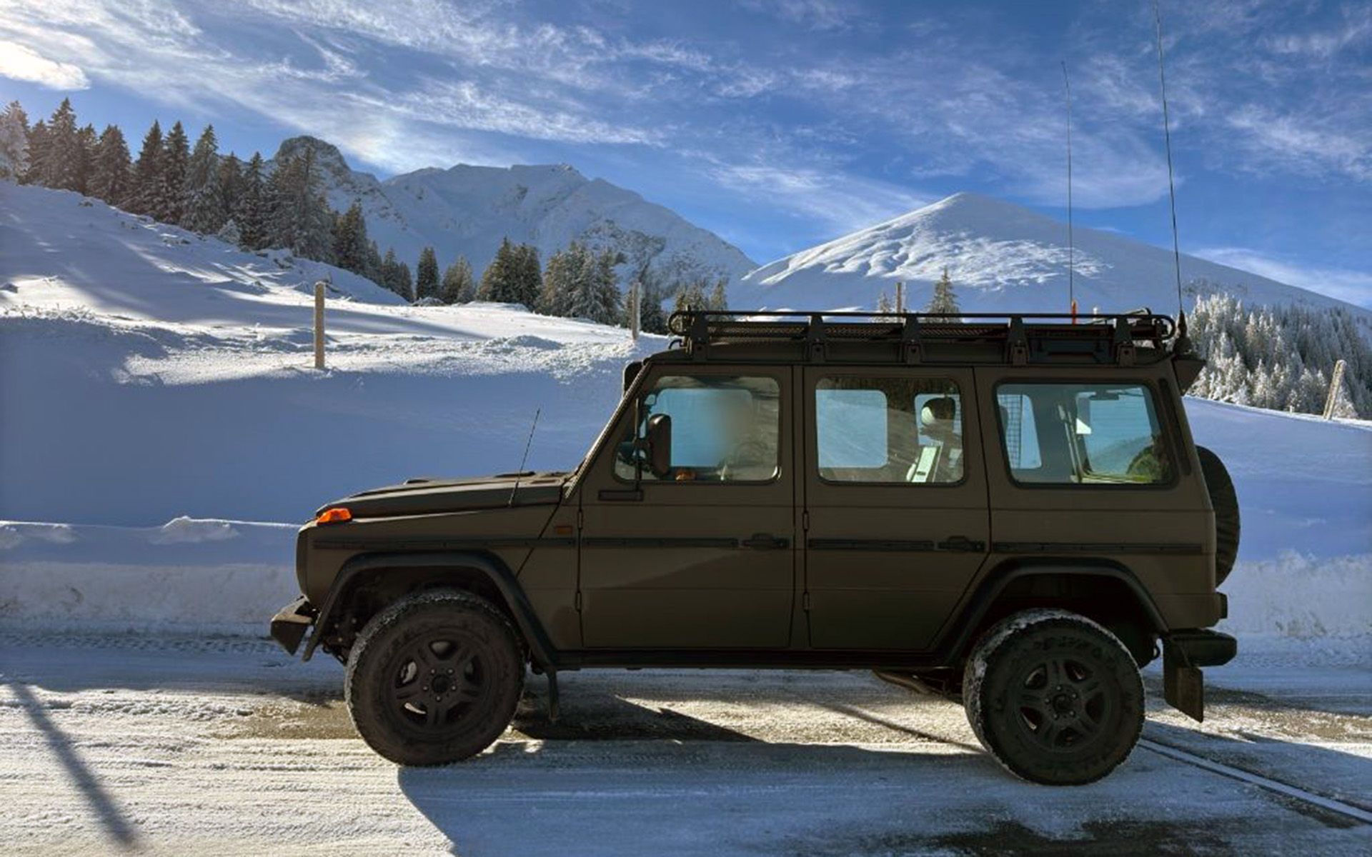 Véhicule militaire sur une route de montagne enneigée. 