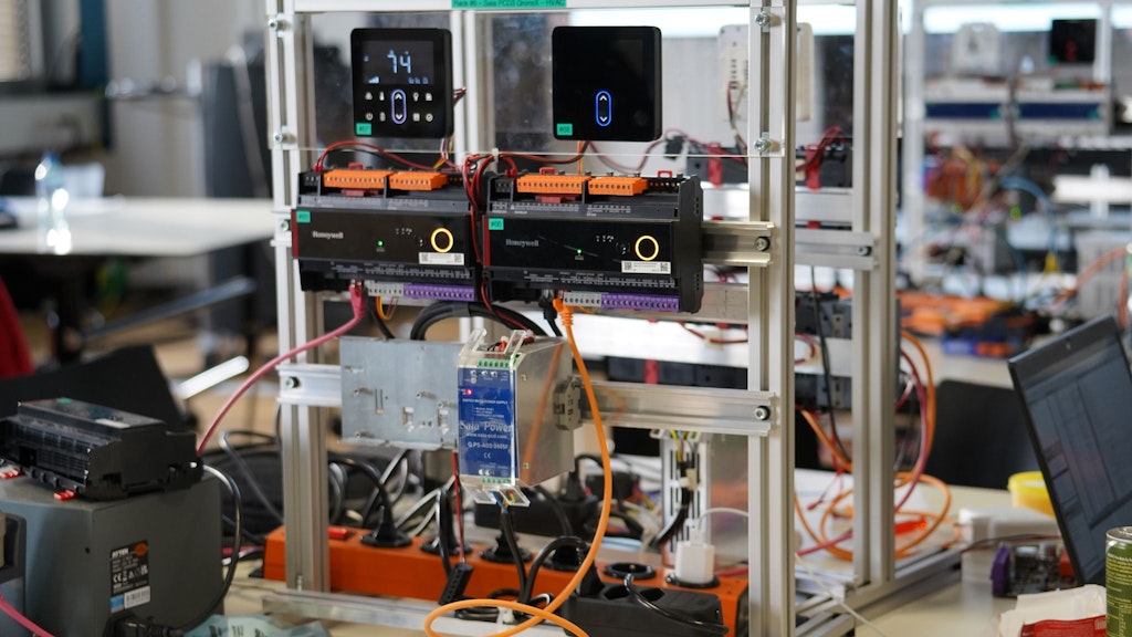 This image shows a complex setup for building automation testing, designed for a research or hackathon event. The main components visible are field devices and controllers related to HVAC (Heating, Ventilation, and Air Conditioning) systems, which are part of the building automation and control infrastructure.