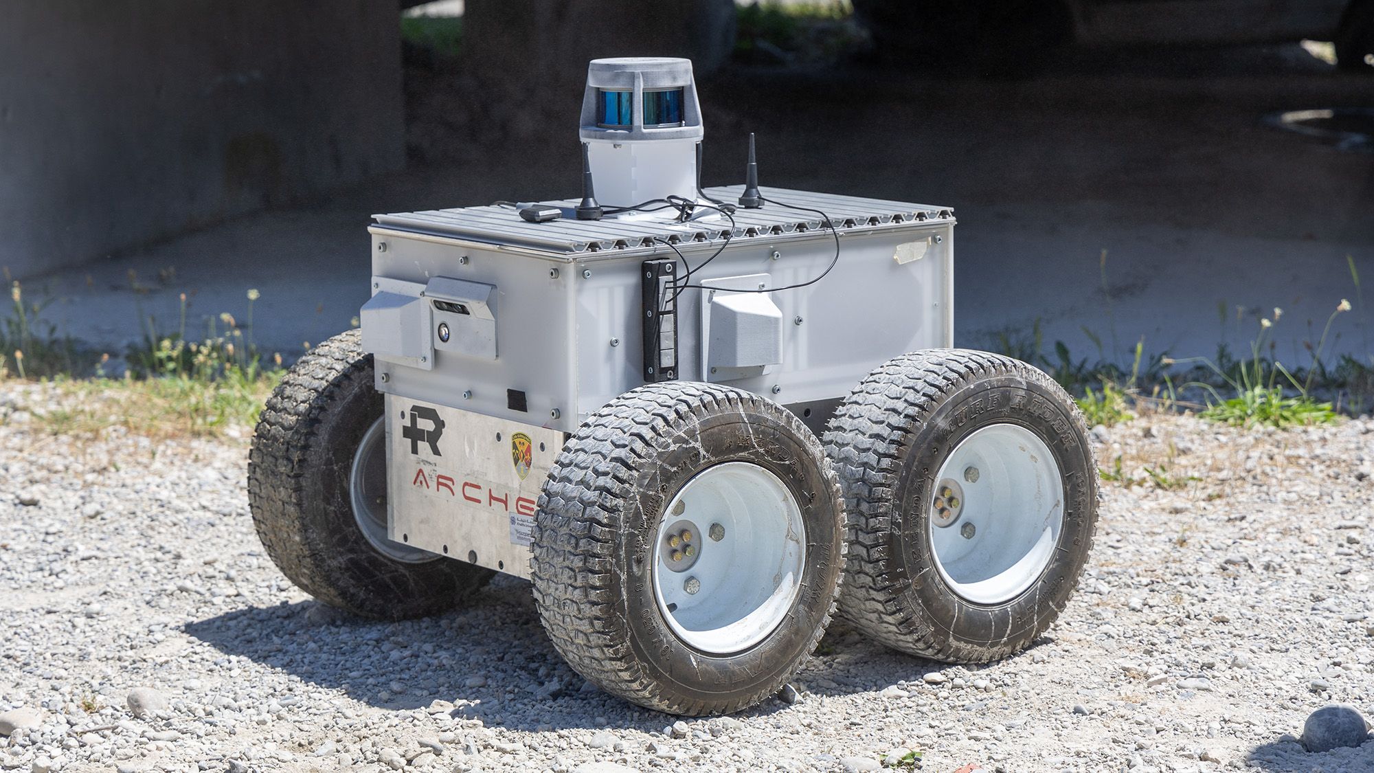 Un robot di Robotic Systems Lab sul selciato di ghiaia davanti a un edificio in calcestruzzo.