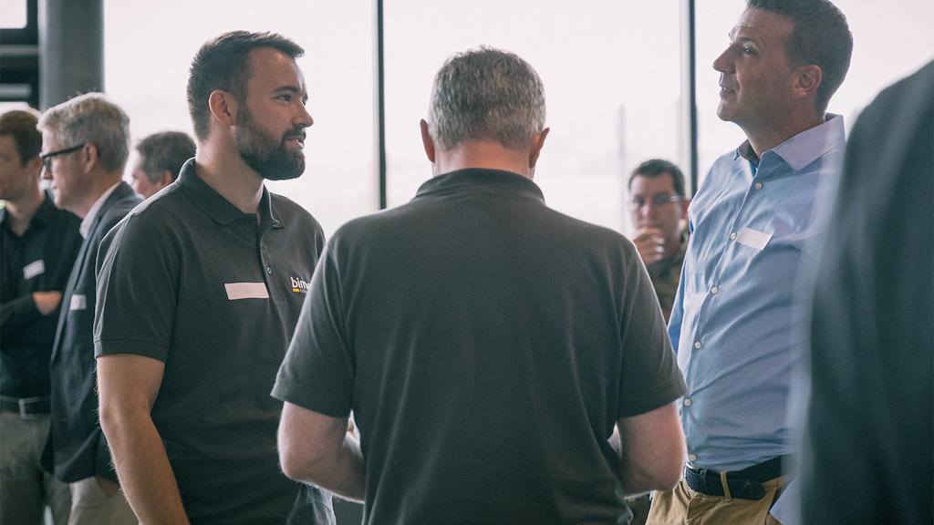 A group of men stand in a circle and talk to each other.