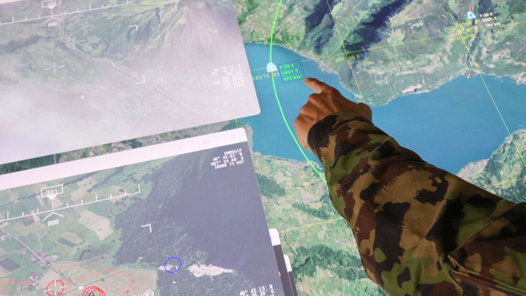 Il soldato indica lo schermo su cui vengono visualizzate le azioni dei partecipanti.