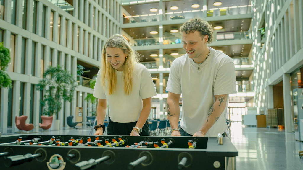 Mann und Frau am Kicker spielen.