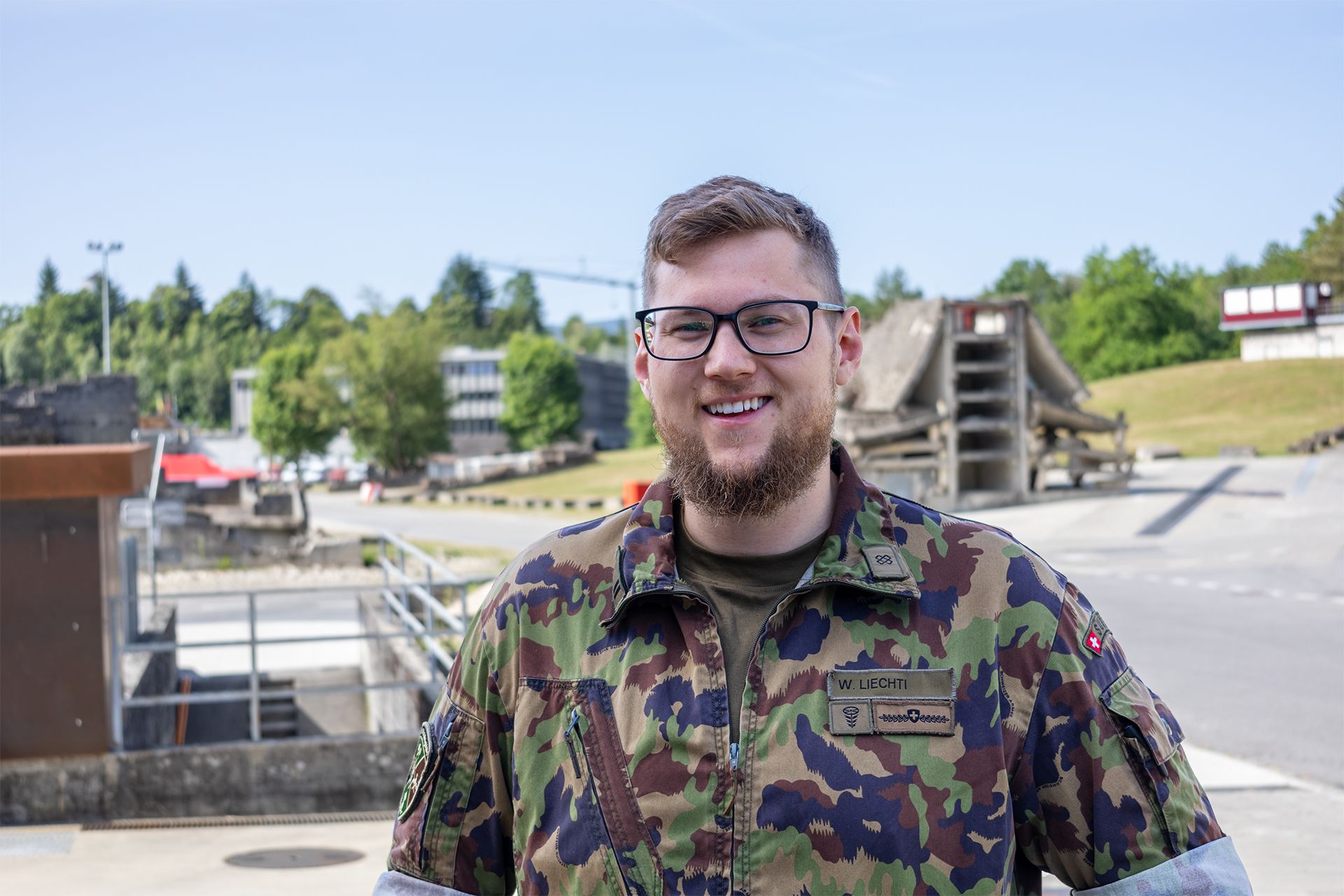 Porträt von einem Vertreter der Schweizer Armee. Im Hintergrund das Übungsdorf Epeisses.