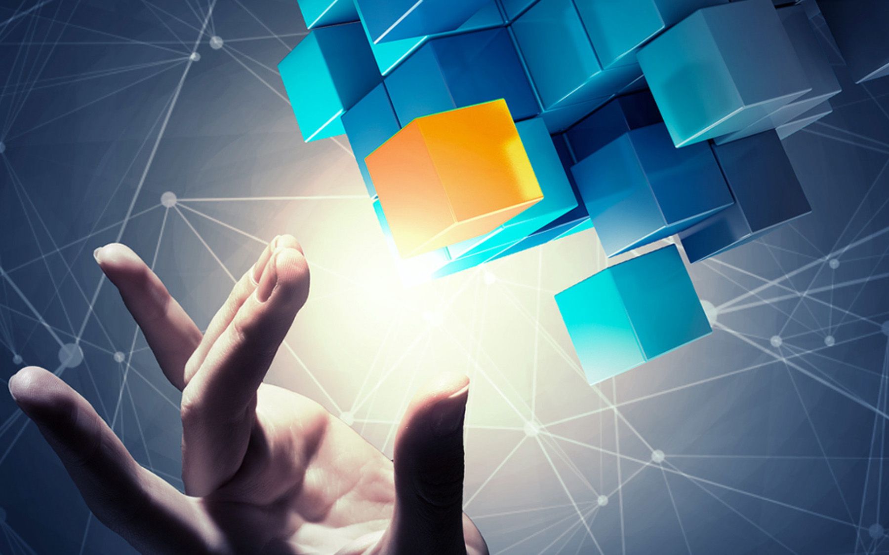 Eine Hand greift nach verschiedenen Kuben in blau und gelb. 