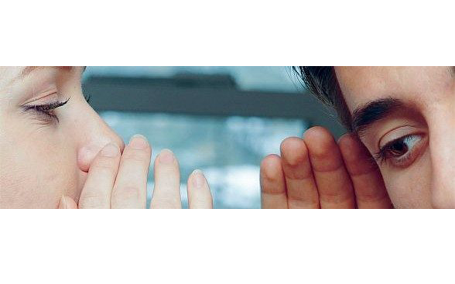 Eine Frau flüstert einem Mann etwas ins Ohr.