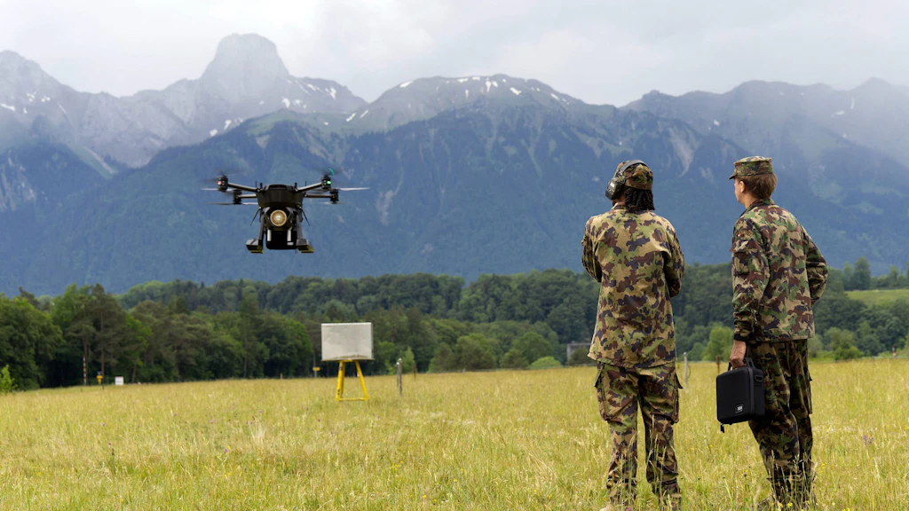 Zwei Angehörige der Armee beobachten eine Transportdrohne während eines Testflugs auf einem Übungsgelände