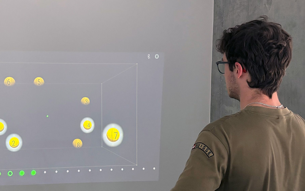 Ein Proband steht vor einer Leinwand. Die Übung einer der Innovationsexpeditionen ist auf die Leinwand projiziert.