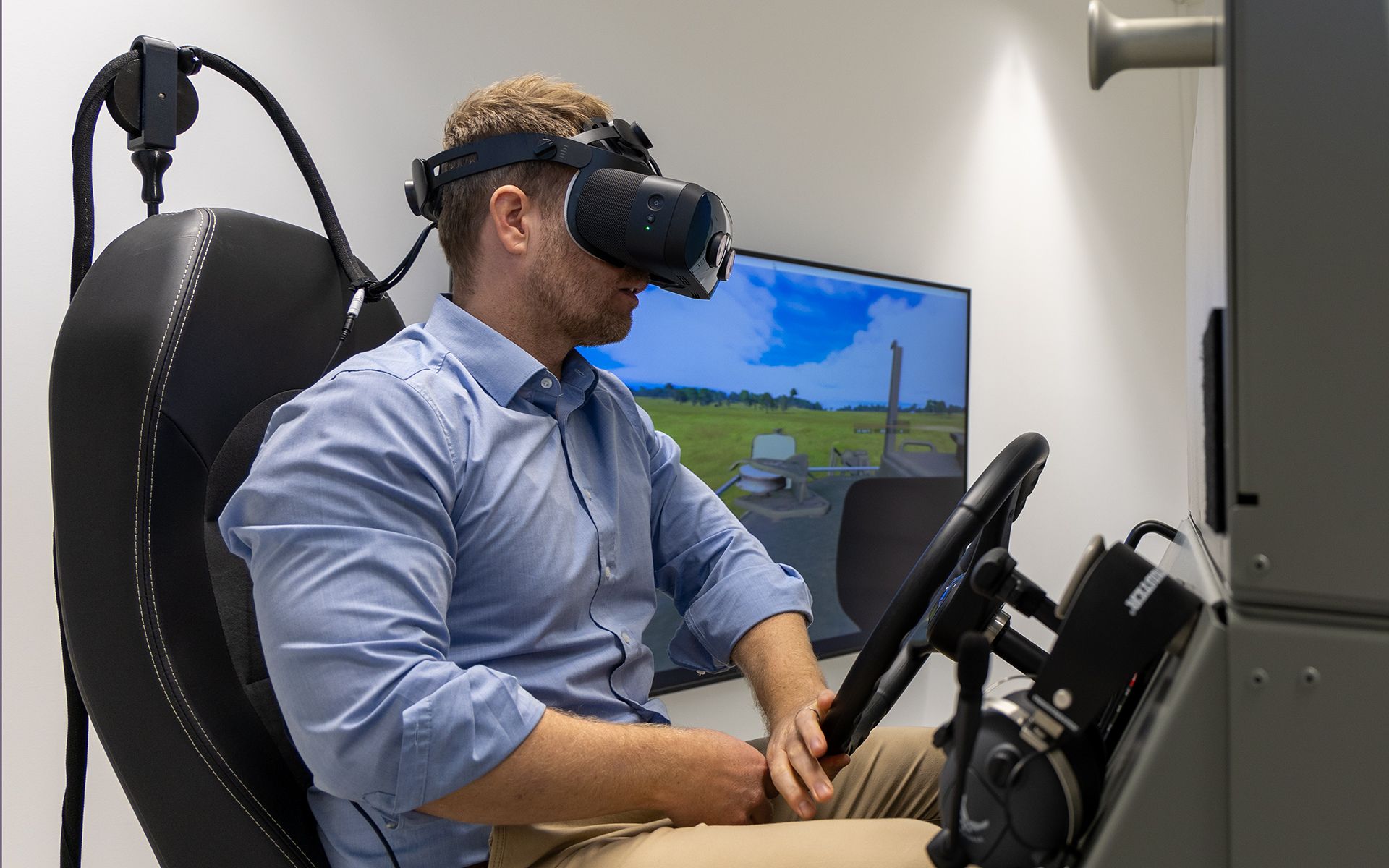 Dr. Michael Rüegsegger sitzt im Simulator, trägt eine VR-Brille und bedient den Simulator. 