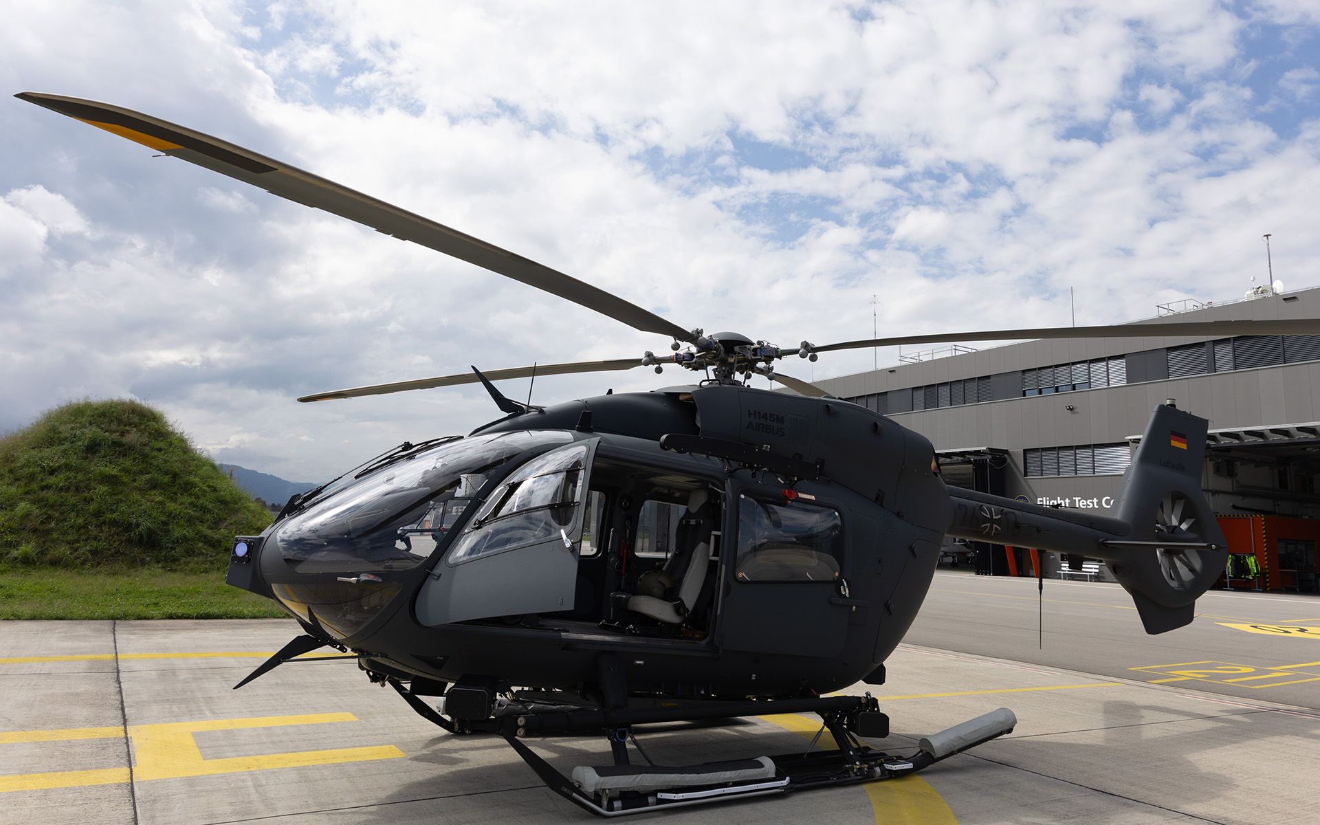 Ein Helikopter mit offener Türe auf dem Startplatz.