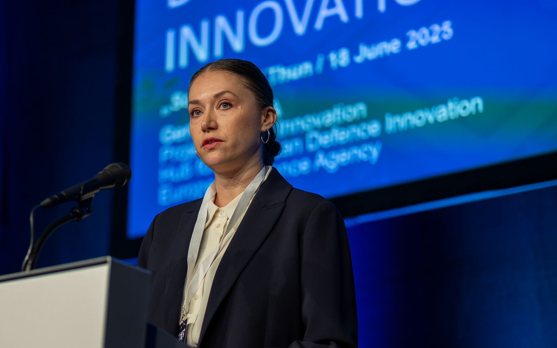 A person is giving a presentation at a lectern in front of a large audience.