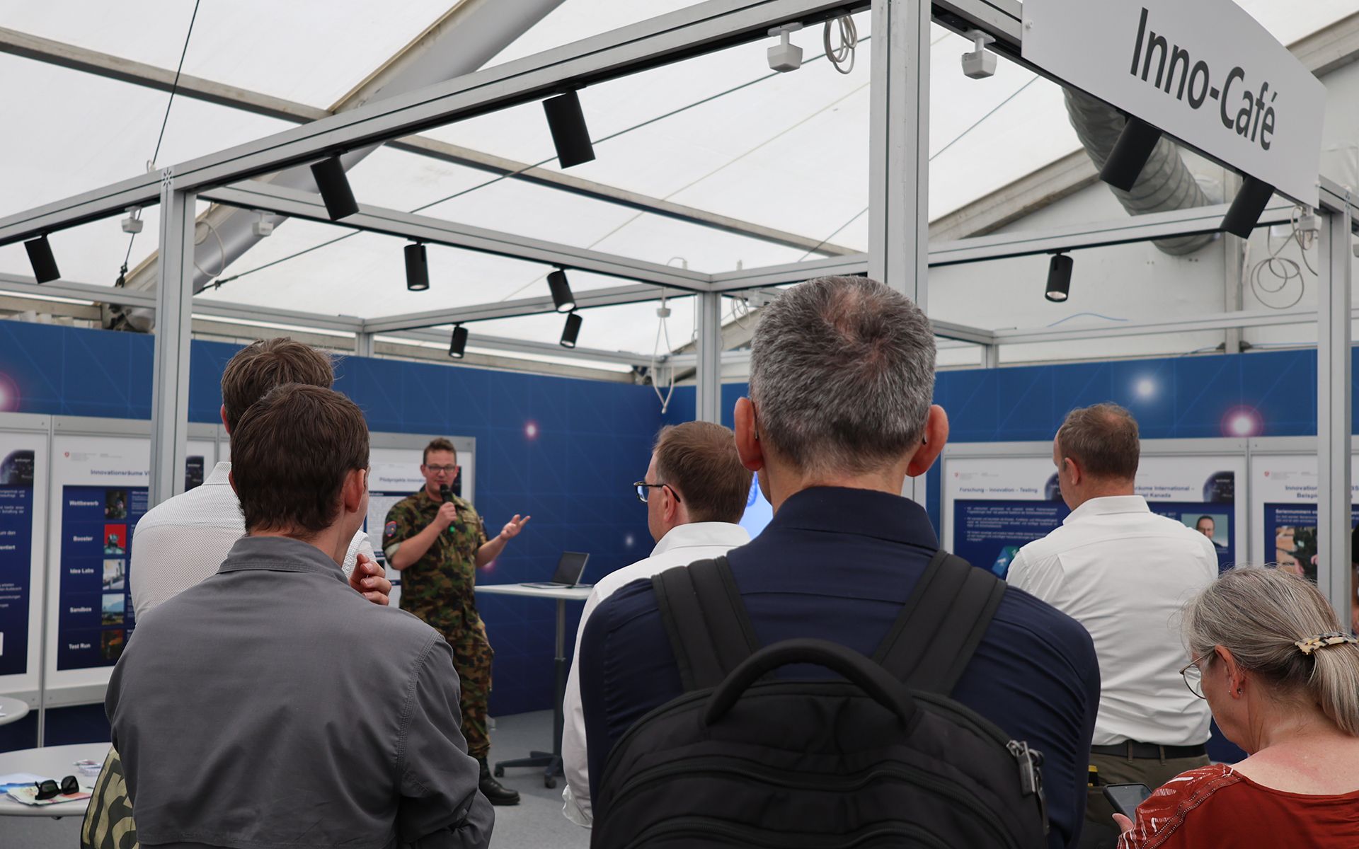 A man holds a presentation for visitors which we can see from behind. 