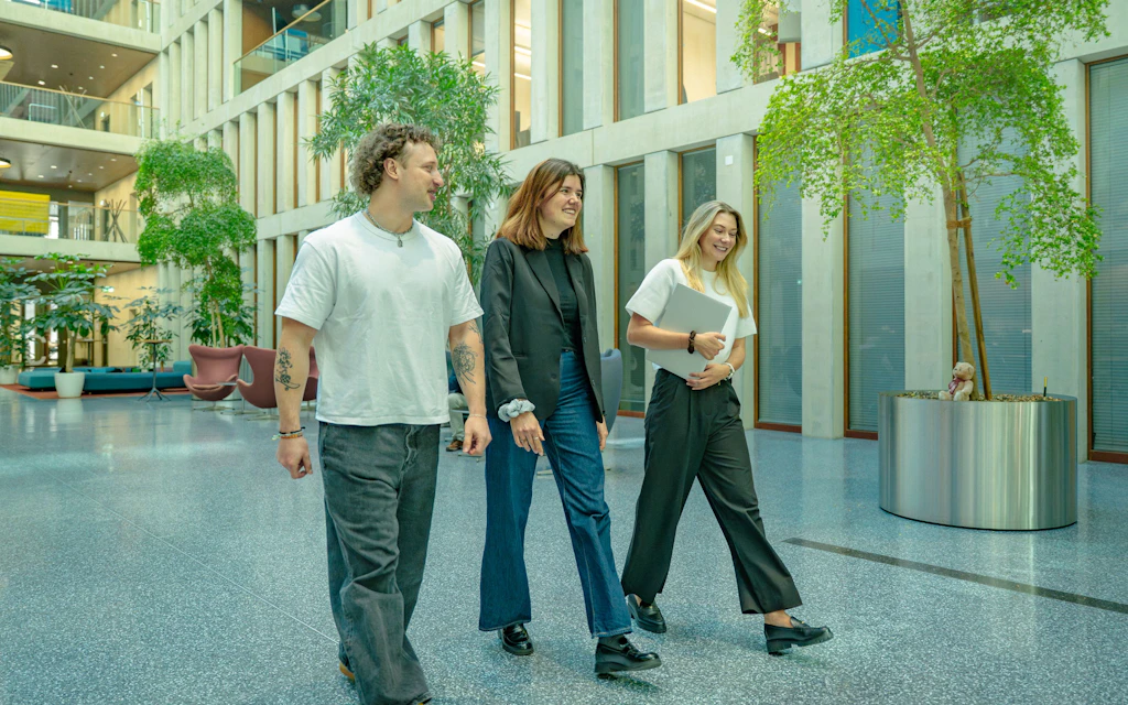 Three university graduates walk through the atrium.