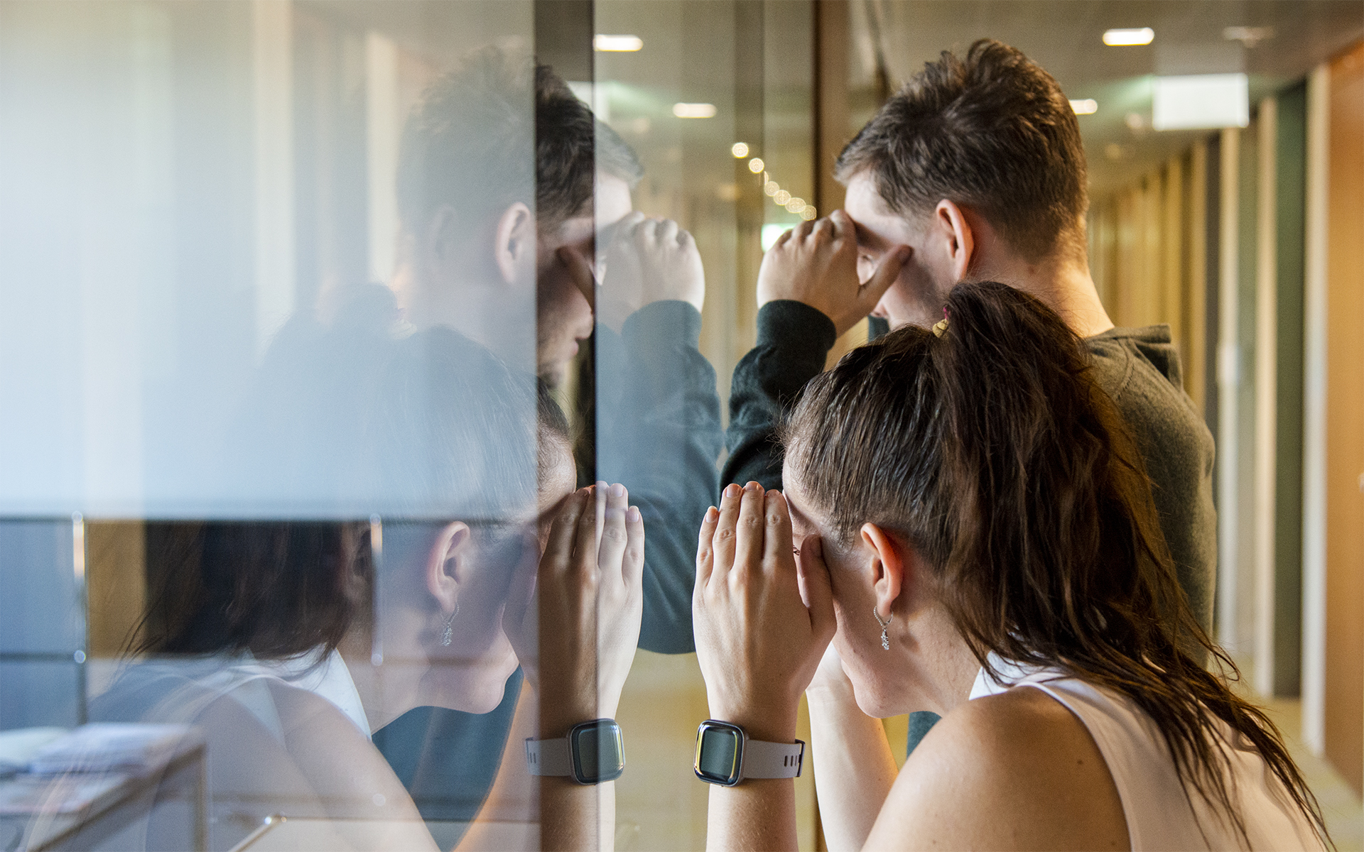 A woman and a man look through a glass wall