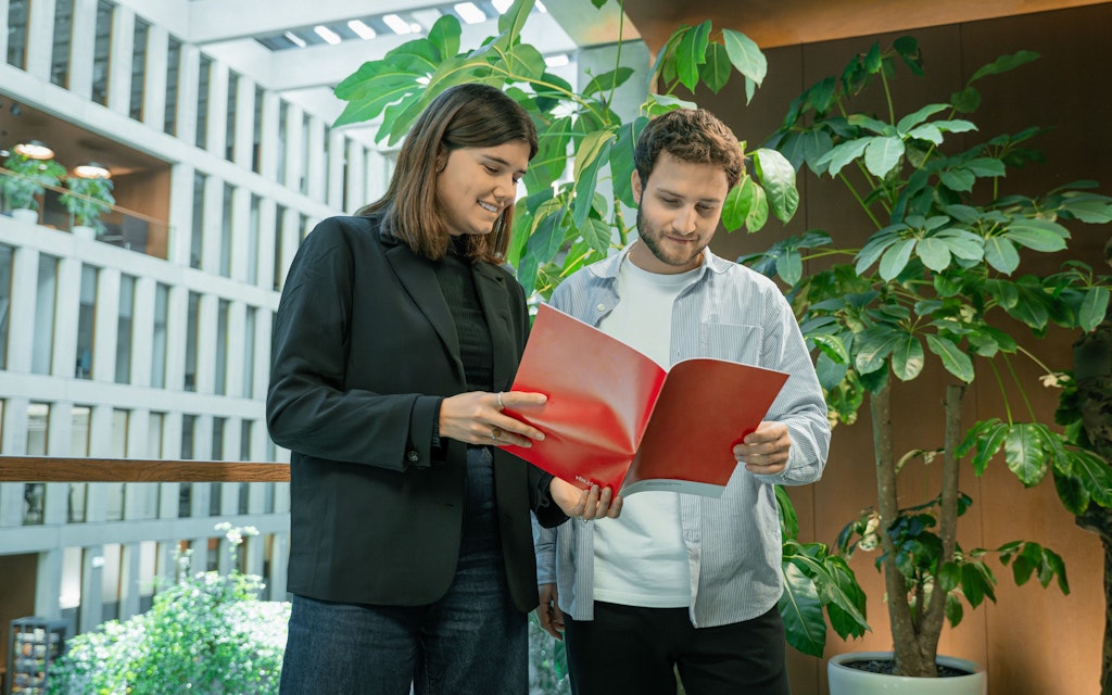 A man and a woman are looking at a booklet.