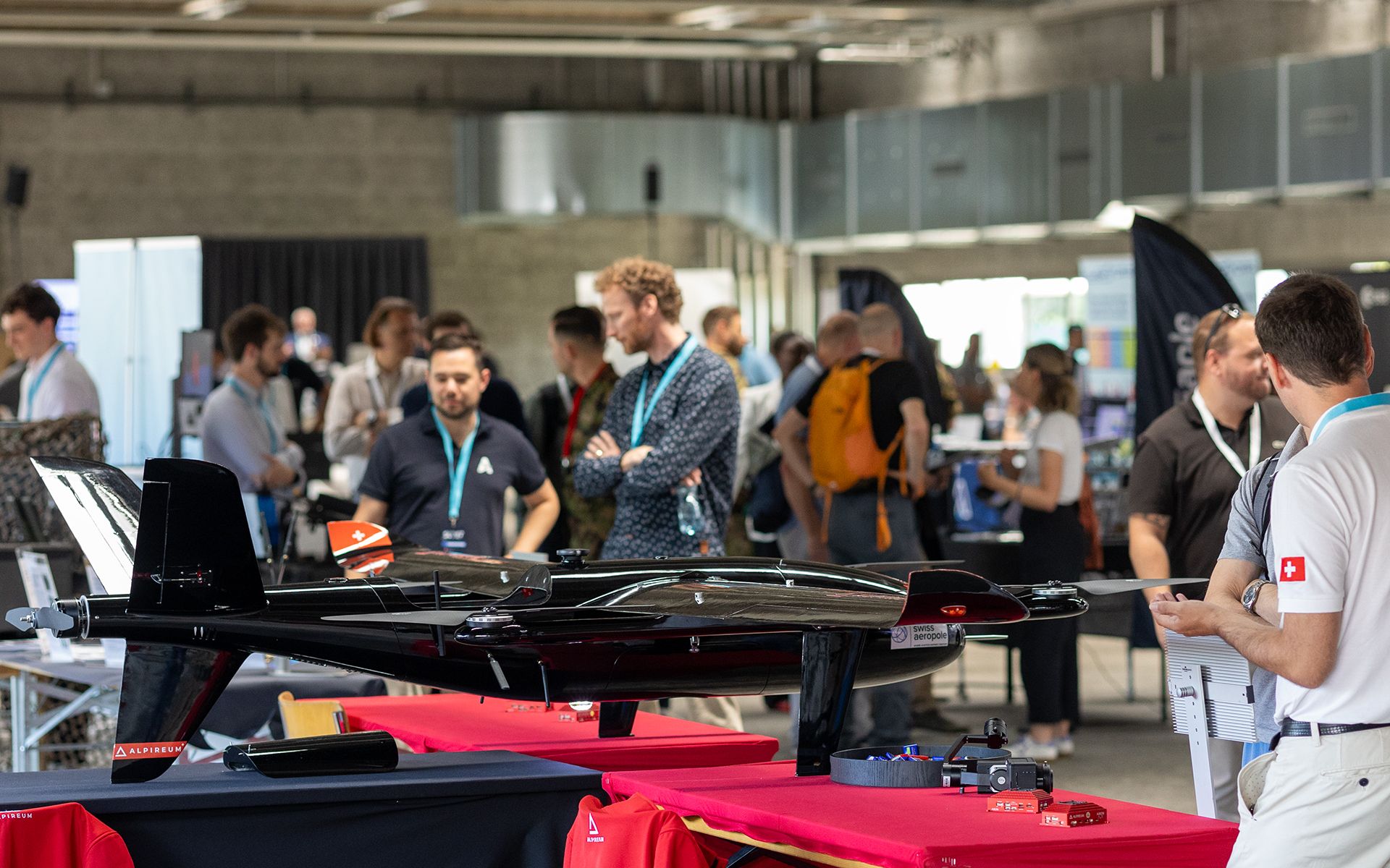An exhibition with various stands and visitors in a large hall.