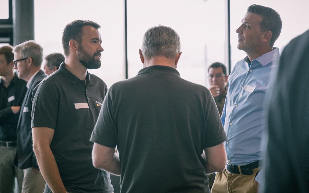 A group of men stand in a circle and talk to each other.
