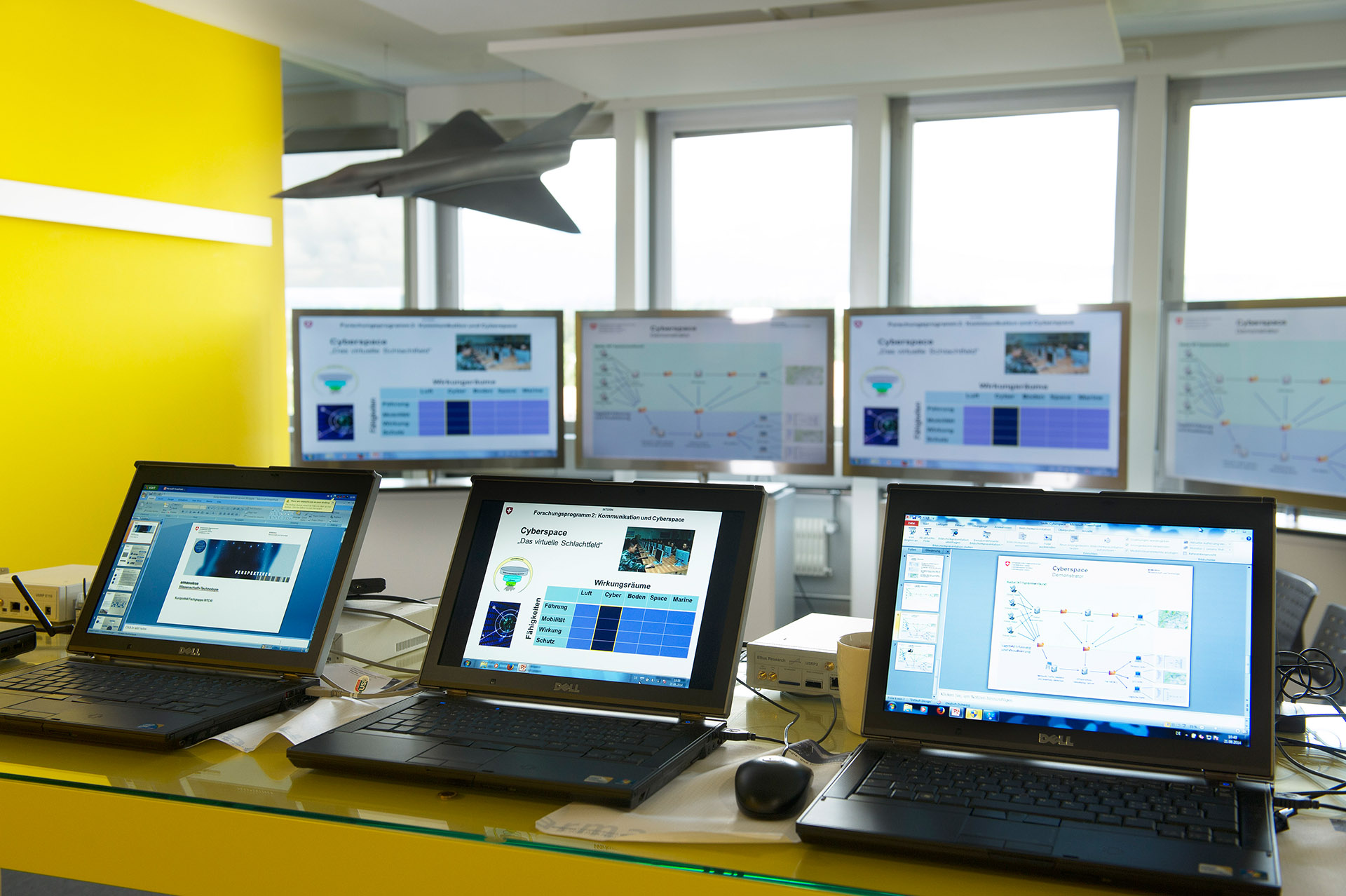 Several screens are placed in a room and on them run various programs