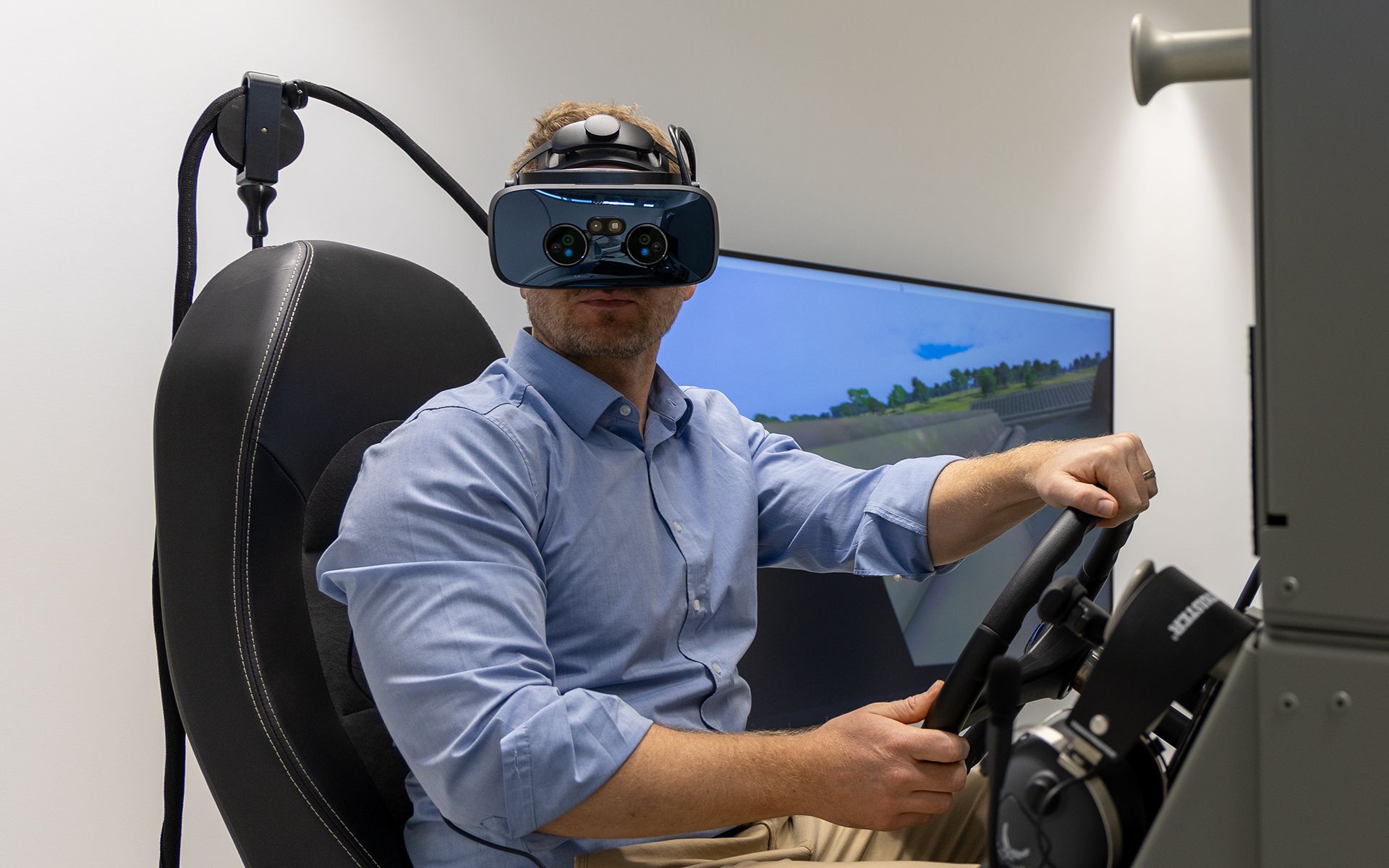 Dr Michael Rüegsegger sits in the simulator, wearing VR glasses and operating the simulator.