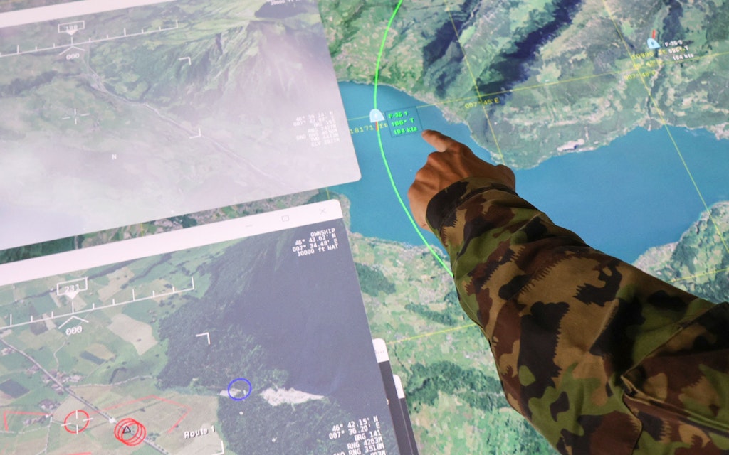 Soldier points to screen displaying participants' actions.