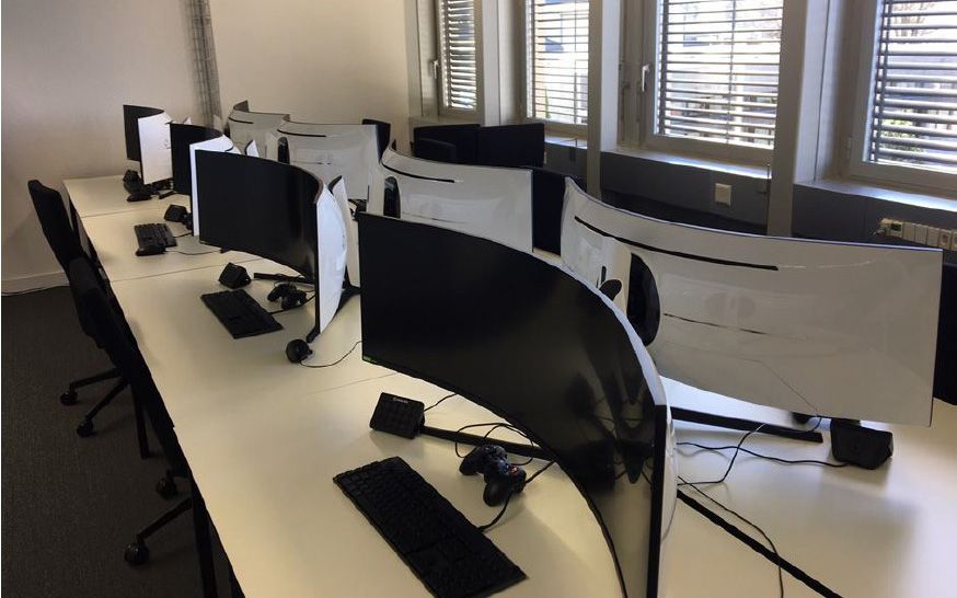 Many large screens are located on tables in a room.