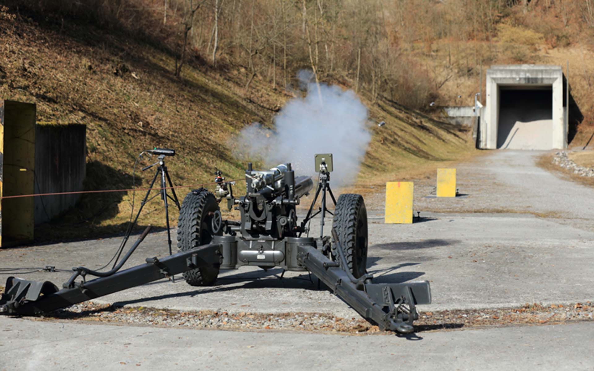 An artillery cannon fires a shot in an open-air measuring stand.