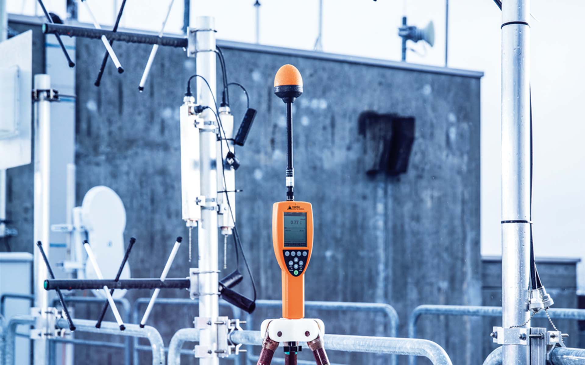 A measuring antenna is located on the roof of a building, surrounded by other antennas.