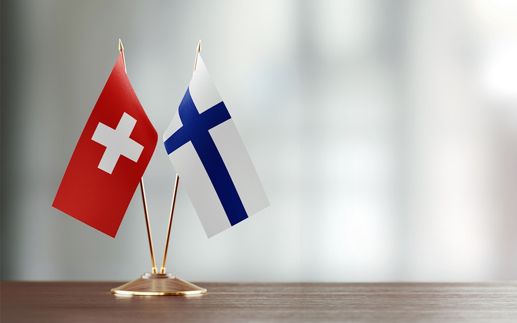 Les drapeaux nationaux suisse et finlandais sont posés sur une table en bois