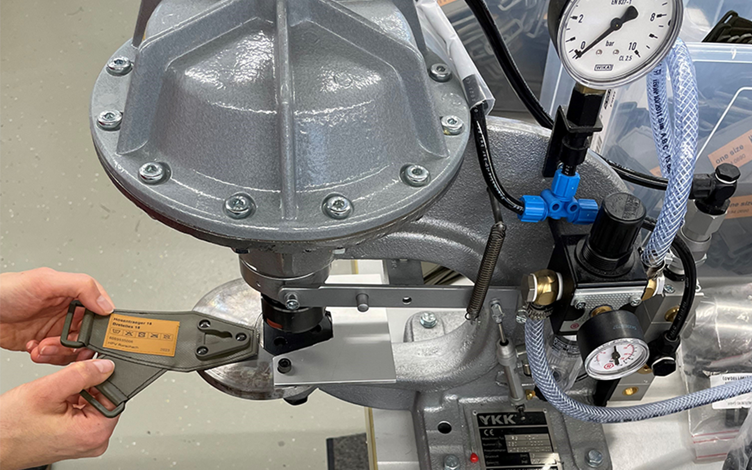 Une collaboratrice poinçonne les rivets dans les boucles de bretelles à l'aide d'une poinçonneuse manuelle.