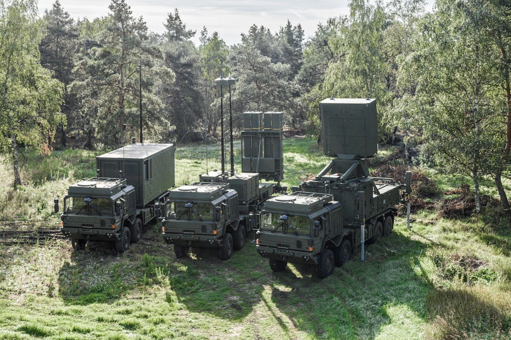 Trois véhicules militaires, garés côte à côte dans une forêt