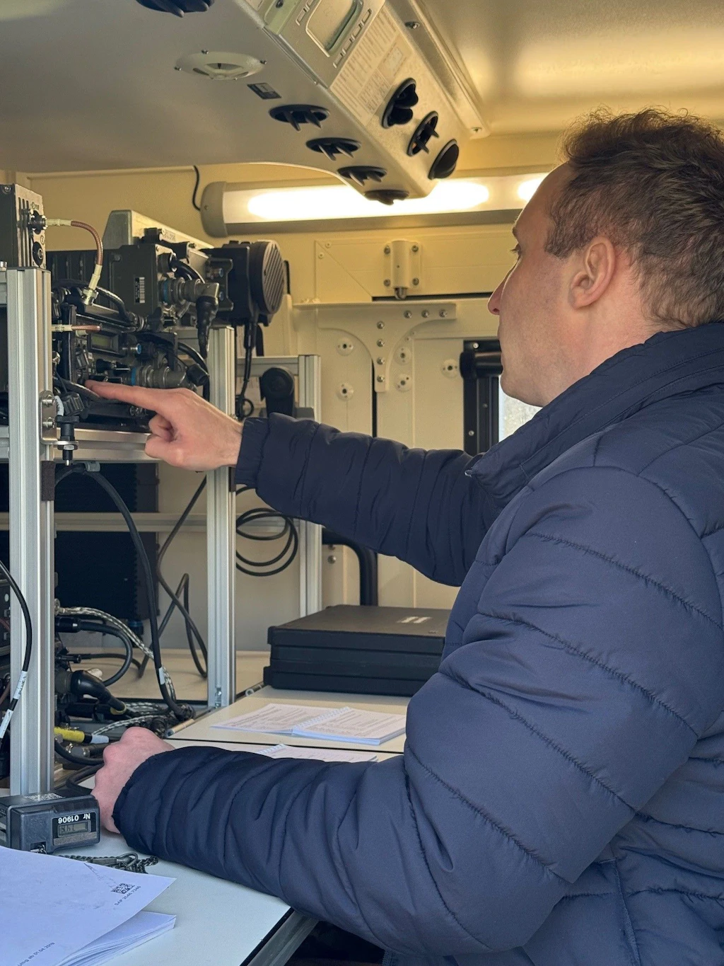 Un homme vérifie et utilise des équipements techniques de radio et d'électronique à bord d'un véhicule