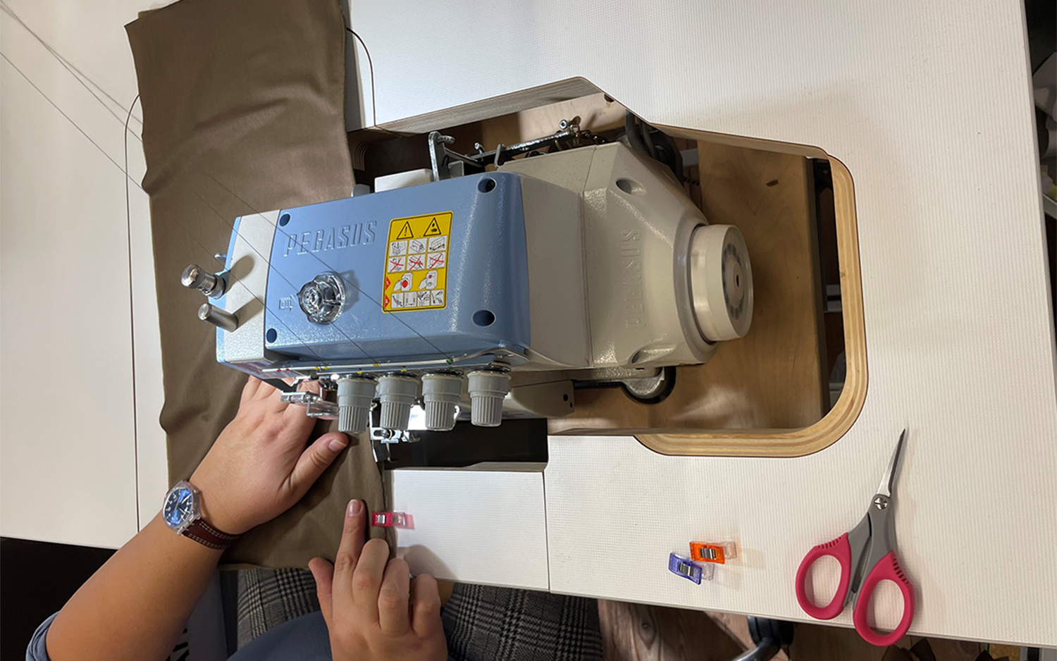 Una collaboratrice cuce lo scaldacollo armasuisse con una macchina industriale per punti overlock