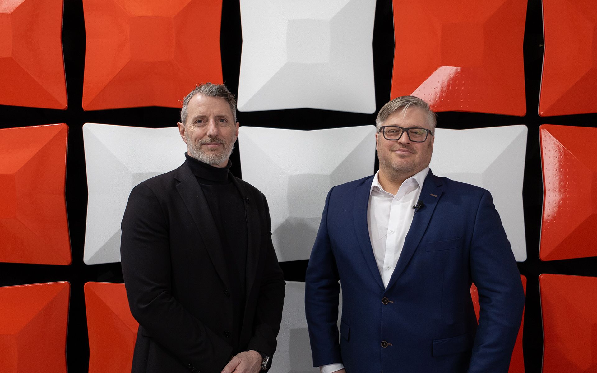 Due uomini in giacca stanno davanti a una grande croce svizzera. 