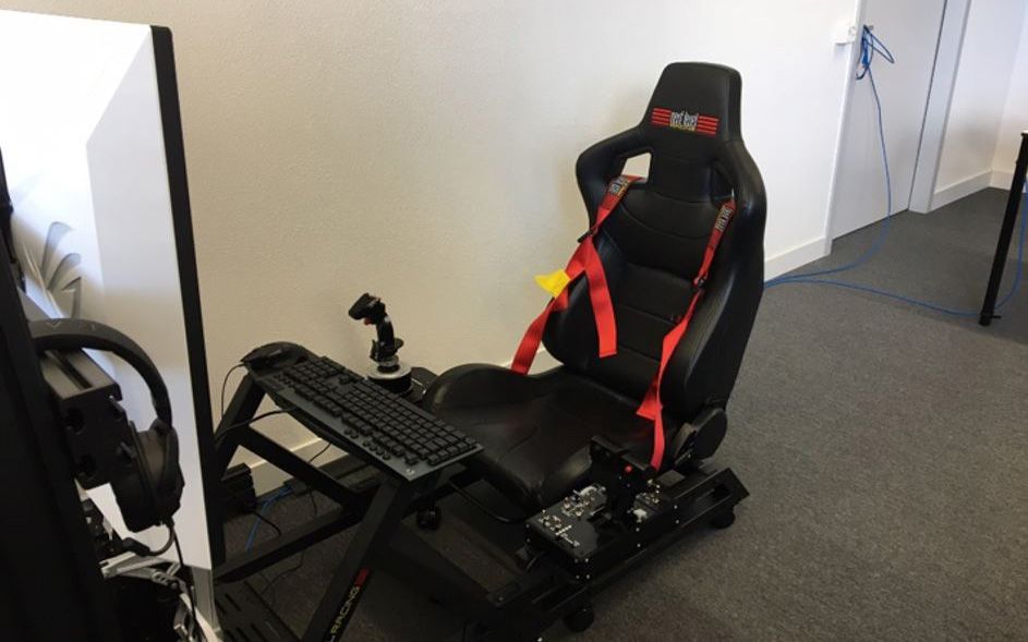 Grande poltrona con joystick e tastiera davanti a uno schermo.