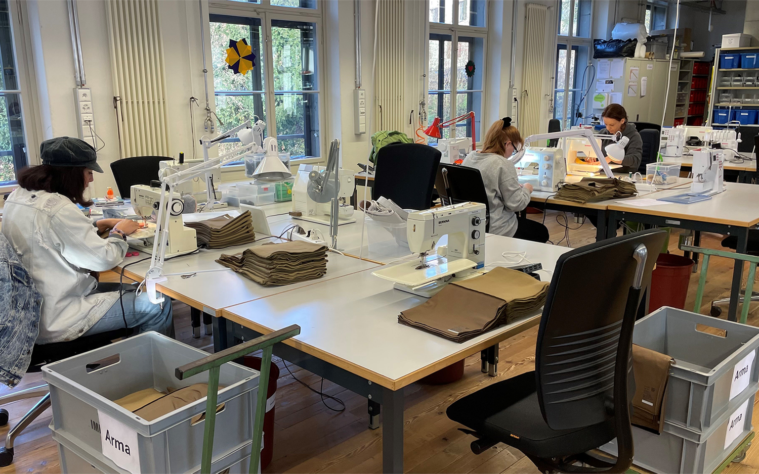 Diversi collaboratori impegnati nel laboratorio sartoriale