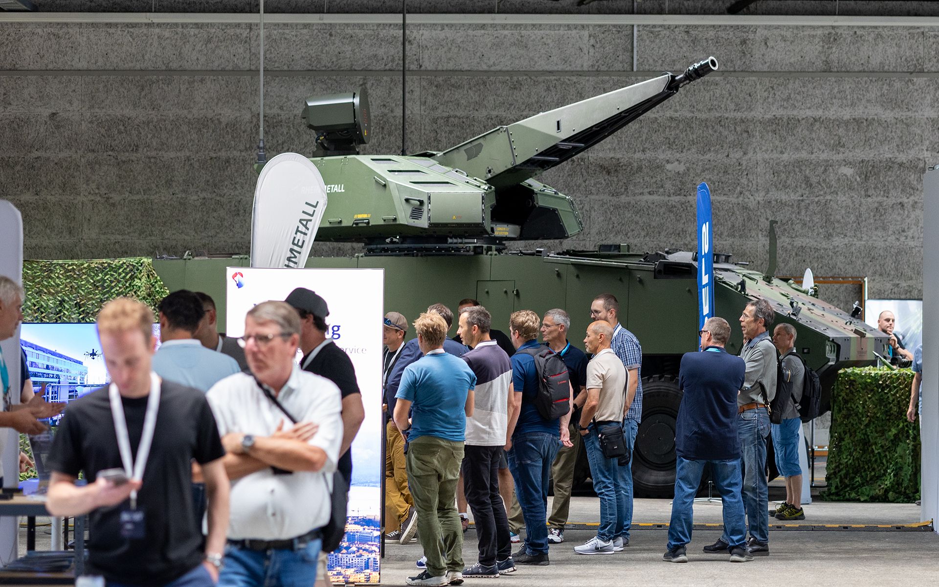 Una mostra con diversi stand e visitatori in un grande padiglione.