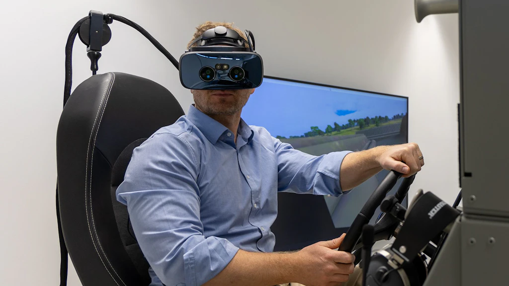 Il dott. Michael Rüegsegger, seduto al simulatore, utilizza quest’ultimo servendosi di un visore per la realtà virtuale